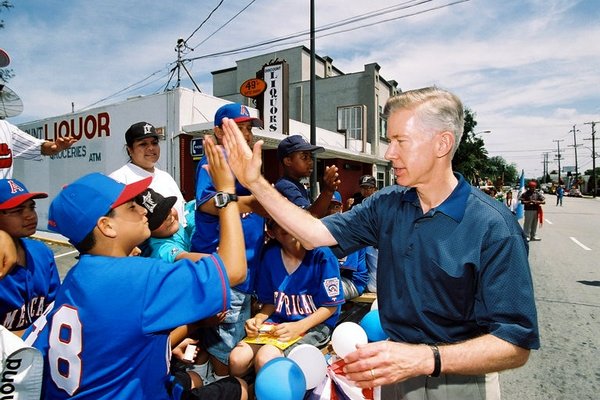 Governor Gray Davis giving a young boy a hi-five during a Fourth of July celebration.